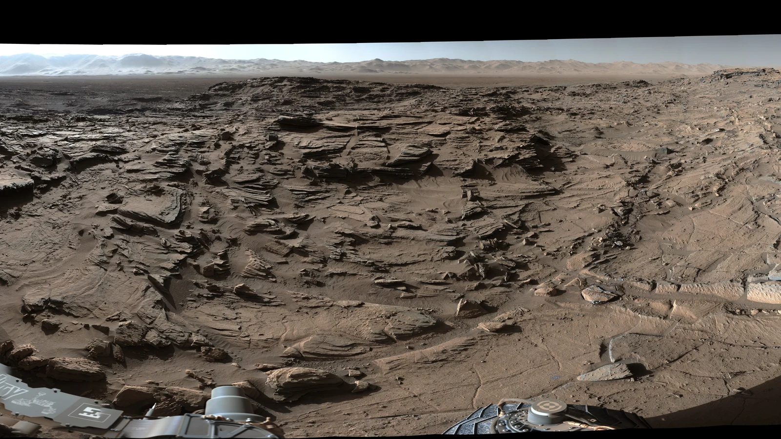 キュリオシティが撮影した、層を持つ岩と遠くの地形を含む火星のパノラマの一部