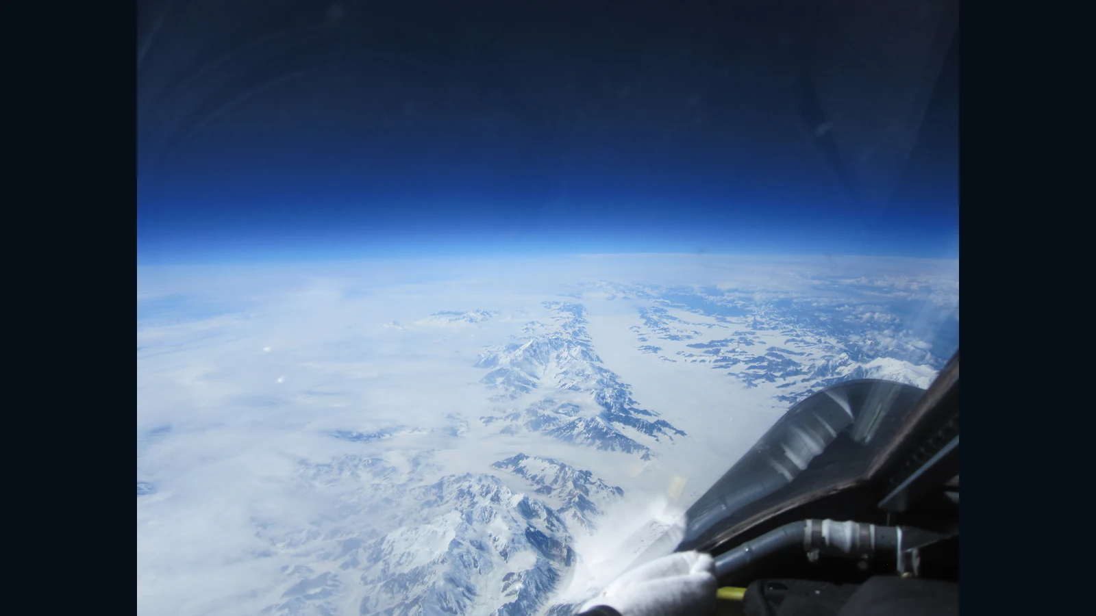 高度約20kmのER-2から見たアラスカのBagley Ice Field。山の稜線と白い氷の表面、手前の機体と窓の反射が見える