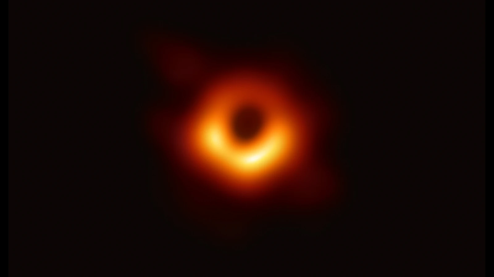 暗い中心を囲む、下側が明るい橙色のリング状のM87観測像