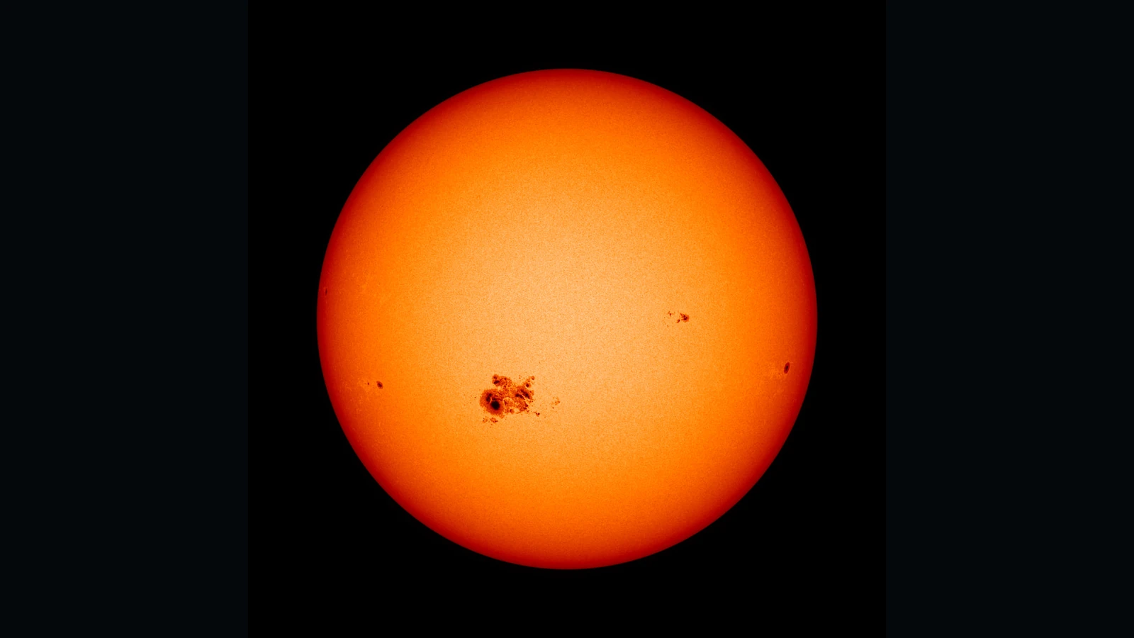 暖色で表示された太陽の円盤。左下寄りに大きな黒点群が見える